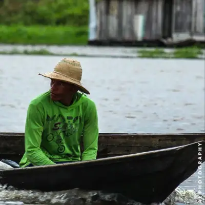 Ribeirinho de chapéu de palha conduzindo sua canoa