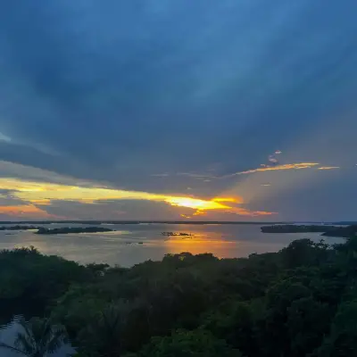 Fim de tarde visto do alto, com a mata em primeiro plano e o rio se abrindo ao fundo